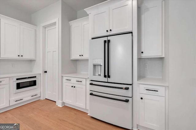 kitchen with light countertops, white appliances, light wood-style flooring, and white cabinets