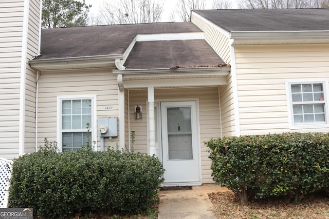 view of exterior entry featuring roof with shingles