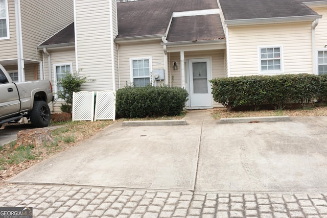 entrance to property featuring a chimney, uncovered parking, and roof with shingles