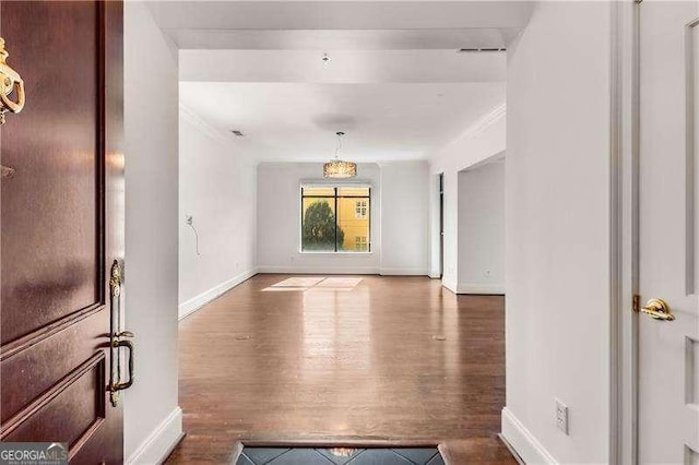 interior space with visible vents, baseboards, wood finished floors, and ornamental molding