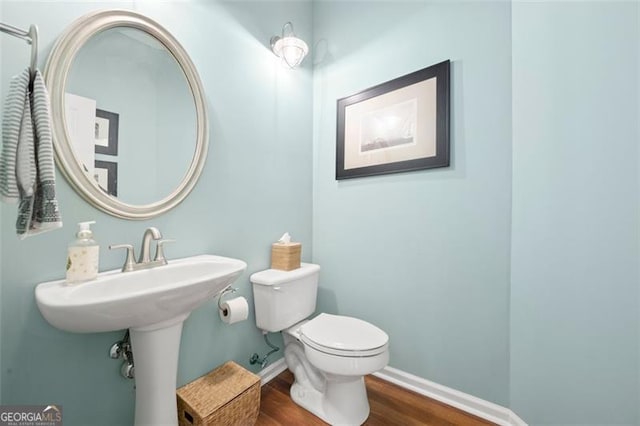 bathroom with toilet, baseboards, and wood finished floors