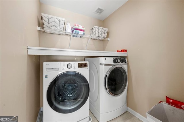 clothes washing area with laundry area, visible vents, baseboards, and washing machine and clothes dryer