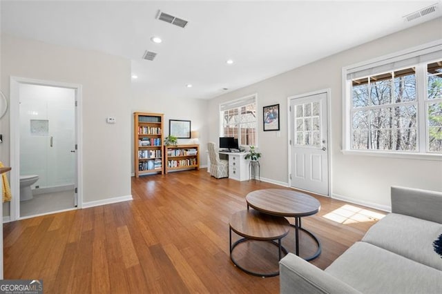 living area with wood finished floors, visible vents, and a healthy amount of sunlight