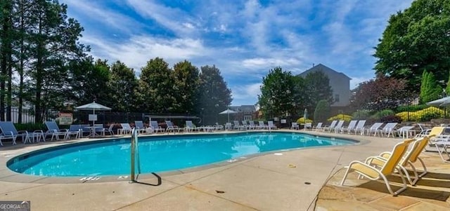 community pool with a patio area and fence