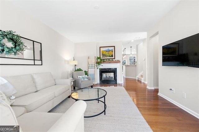 living room featuring stairs, wood finished floors, a high end fireplace, and baseboards