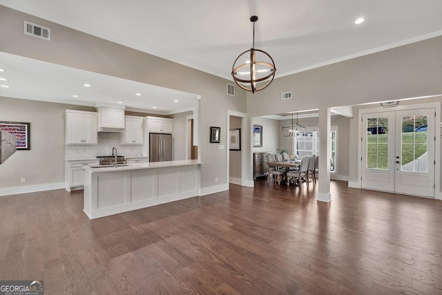 kitchen featuring a chandelier, premium range hood, a sink, visible vents, and stainless steel refrigerator