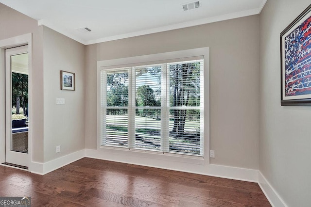 interior space featuring dark wood-type flooring, visible vents, ornamental molding, and baseboards