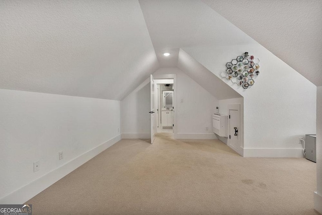 bonus room featuring vaulted ceiling, a textured ceiling, carpet flooring, and baseboards