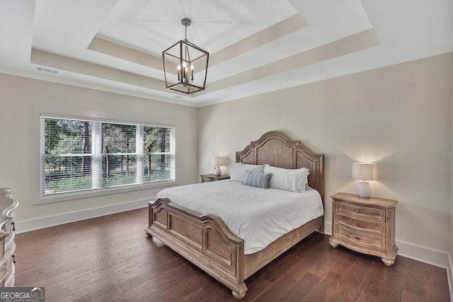 bedroom with dark wood-style floors, a tray ceiling, an inviting chandelier, and baseboards