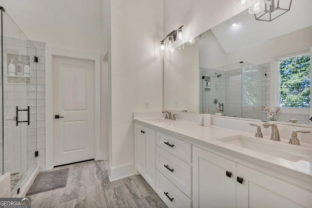 full bath with double vanity, a stall shower, a sink, and lofted ceiling