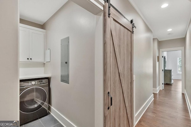 washroom featuring washer / dryer, a barn door, electric panel, baseboards, and cabinet space