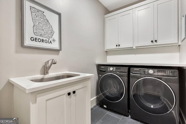 clothes washing area with cabinet space, a sink, washer and clothes dryer, and dark tile patterned floors