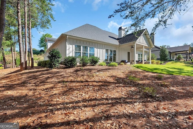 back of property featuring board and batten siding, a yard, and a chimney