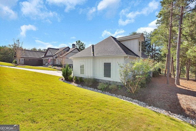 view of property exterior with board and batten siding, a yard, and a shingled roof