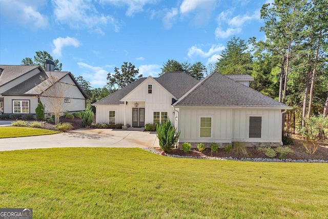 view of front of home featuring driveway, a shingled roof, a front lawn, and board and batten siding