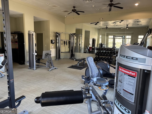 exercise room featuring visible vents, a ceiling fan, and light colored carpet