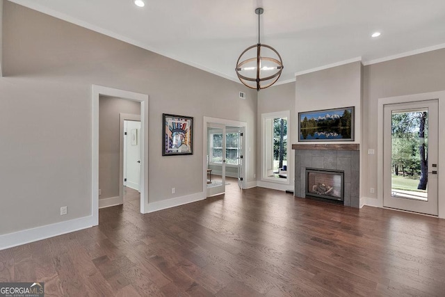 unfurnished living room with ornamental molding, dark wood-style flooring, a tile fireplace, and baseboards