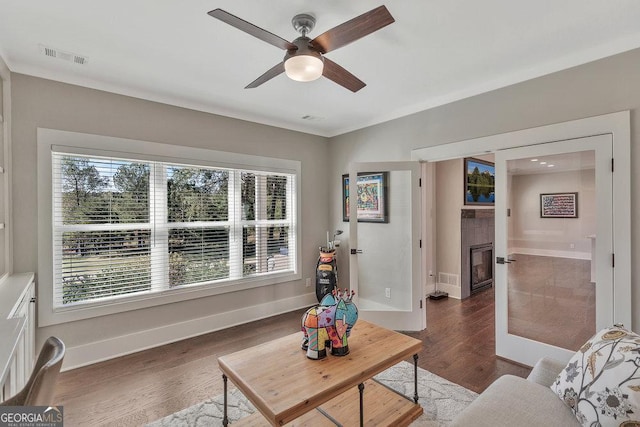 living area with ceiling fan, wood finished floors, visible vents, and baseboards