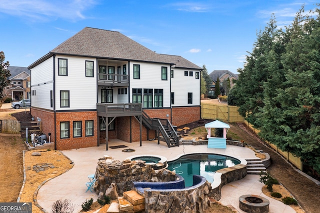 back of house featuring brick siding, an outdoor fire pit, a patio area, a balcony, and stairs