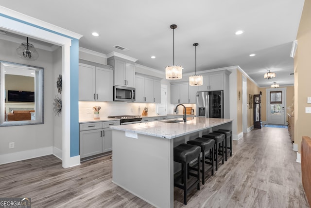 kitchen with visible vents, gray cabinetry, appliances with stainless steel finishes, ornamental molding, and a sink