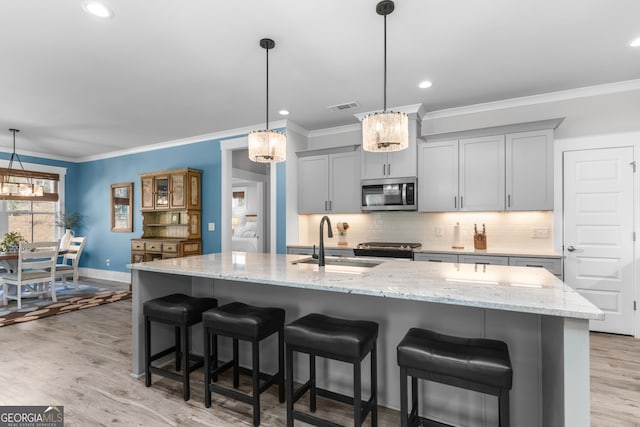 kitchen with light wood finished floors, visible vents, decorative backsplash, stainless steel microwave, and gray cabinets