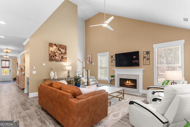 living room featuring light wood finished floors, stairs, a premium fireplace, and baseboards