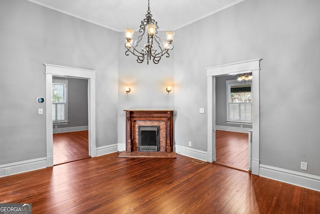 unfurnished living room featuring a wealth of natural light, a brick fireplace, visible vents, and hardwood / wood-style flooring