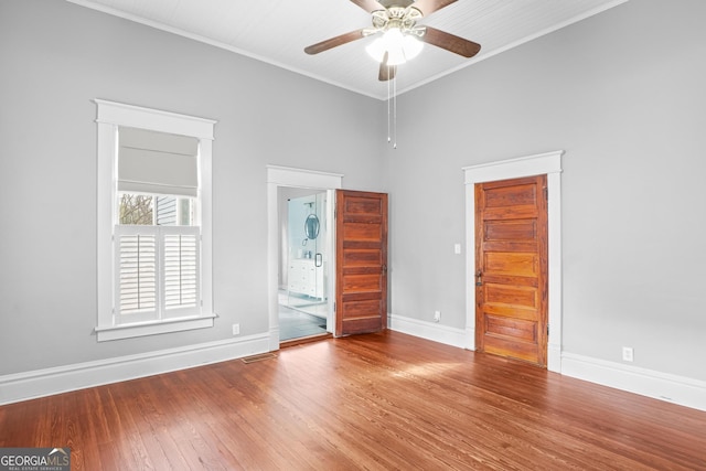 unfurnished bedroom featuring crown molding, baseboards, wood finished floors, and ensuite bathroom