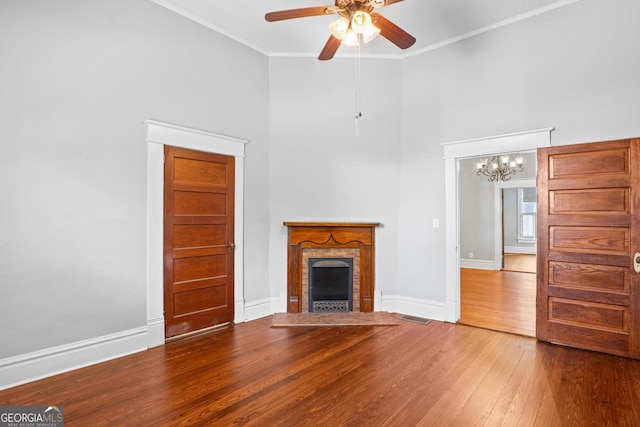 unfurnished living room featuring crown molding, visible vents, a brick fireplace, wood finished floors, and baseboards