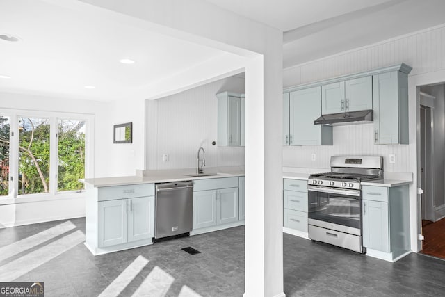 kitchen featuring stainless steel appliances, tasteful backsplash, light countertops, a sink, and under cabinet range hood