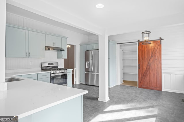 kitchen with under cabinet range hood, a barn door, stainless steel appliances, and light countertops