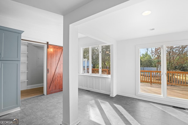 interior space with a healthy amount of sunlight, a barn door, visible vents, and recessed lighting