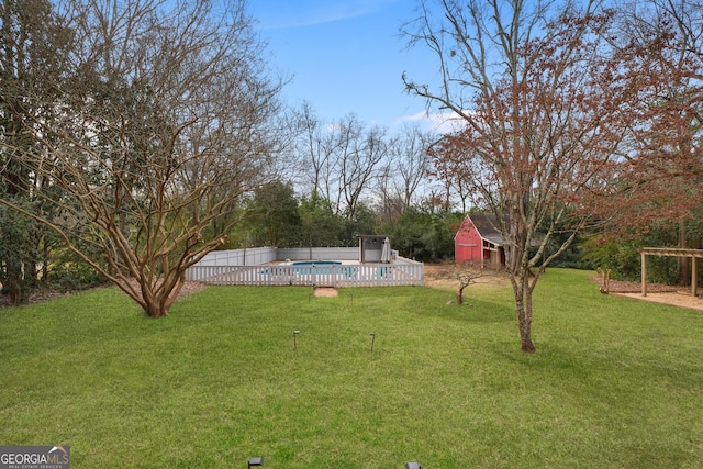 view of yard with a fenced in pool, an outbuilding, fence, and a storage shed