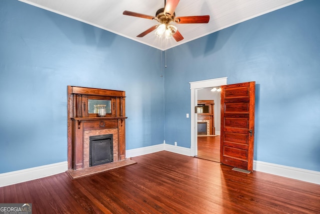 unfurnished living room featuring a fireplace with raised hearth, baseboards, and wood finished floors