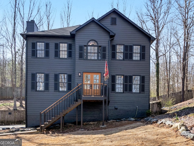 view of front of home featuring stairs, french doors, a chimney, and fence