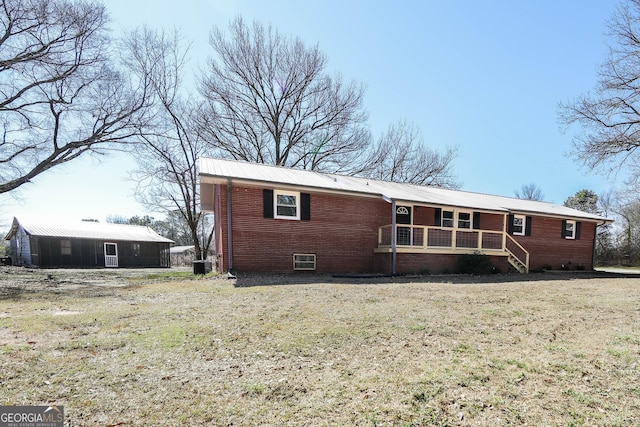 rear view of property featuring a porch, brick siding, and a lawn