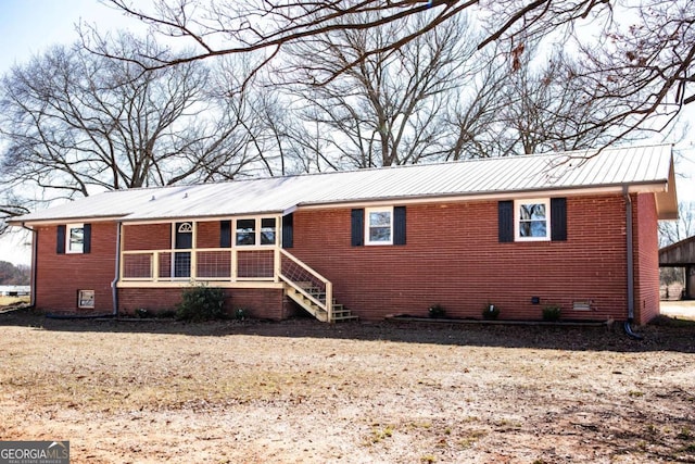 ranch-style house with a porch, brick siding, and metal roof