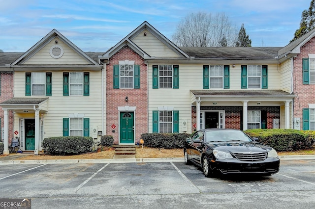 view of property featuring uncovered parking and brick siding