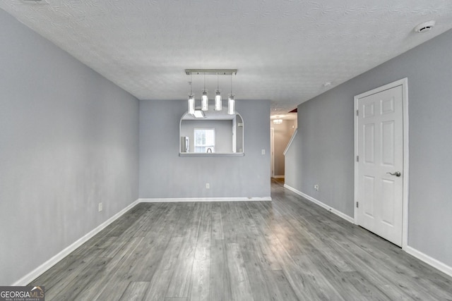 spare room with baseboards, a textured ceiling, and wood finished floors