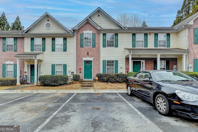 townhome / multi-family property with uncovered parking and brick siding