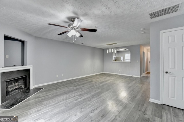 unfurnished living room featuring visible vents, baseboards, a fireplace, wood finished floors, and a ceiling fan