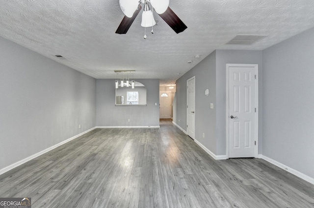 unfurnished living room with a ceiling fan, wood finished floors, visible vents, and baseboards