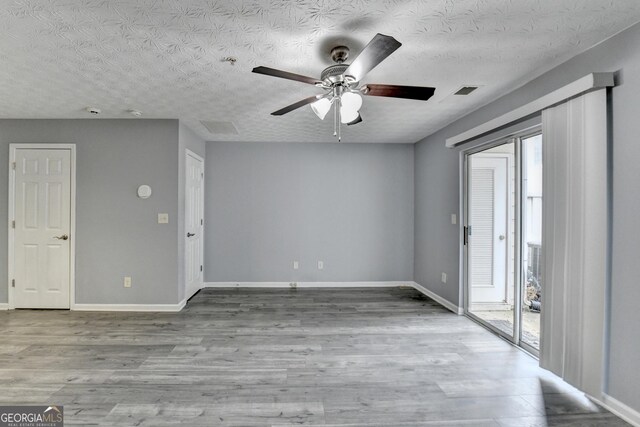 empty room with ceiling fan, baseboards, a textured ceiling, and wood finished floors