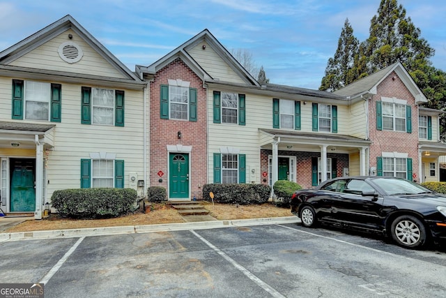 townhome / multi-family property with brick siding and uncovered parking