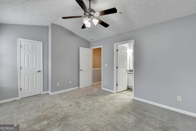 unfurnished bedroom featuring baseboards, carpet floors, a textured ceiling, and vaulted ceiling