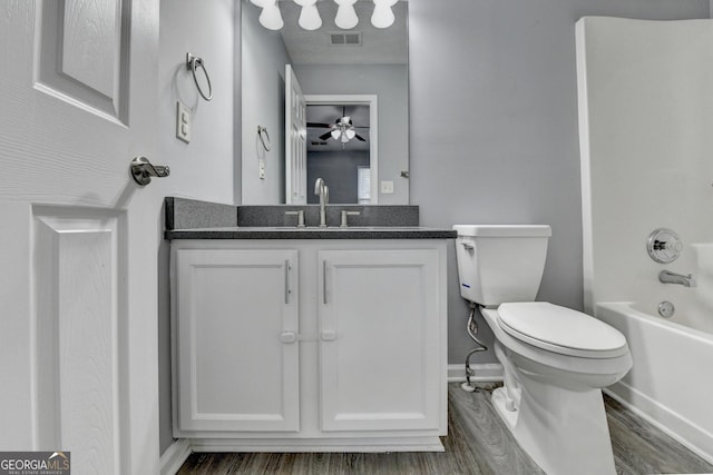 bathroom with vanity, toilet, wood finished floors, and visible vents