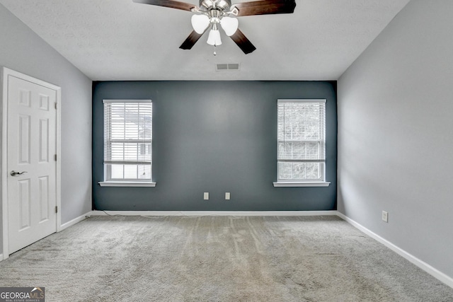 carpeted empty room featuring a textured ceiling, baseboards, visible vents, and ceiling fan