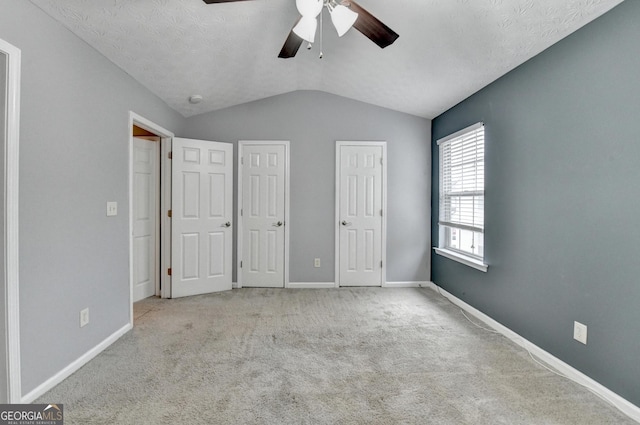 unfurnished bedroom with multiple closets, ceiling fan, baseboards, vaulted ceiling, and carpet flooring