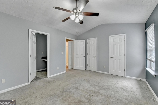 unfurnished bedroom with lofted ceiling, baseboards, carpet floors, and a textured ceiling