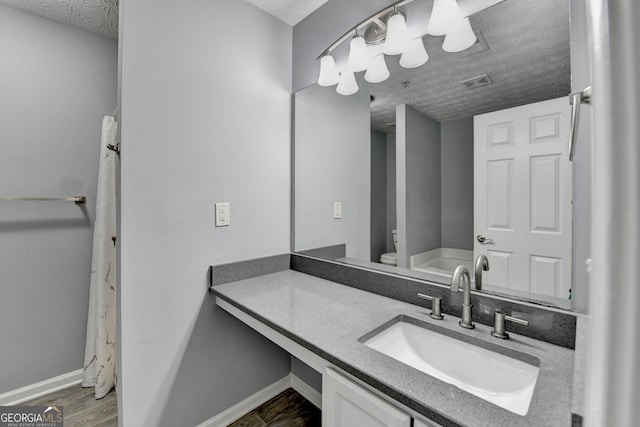 full bathroom featuring vanity, wood finished floors, visible vents, and a textured ceiling